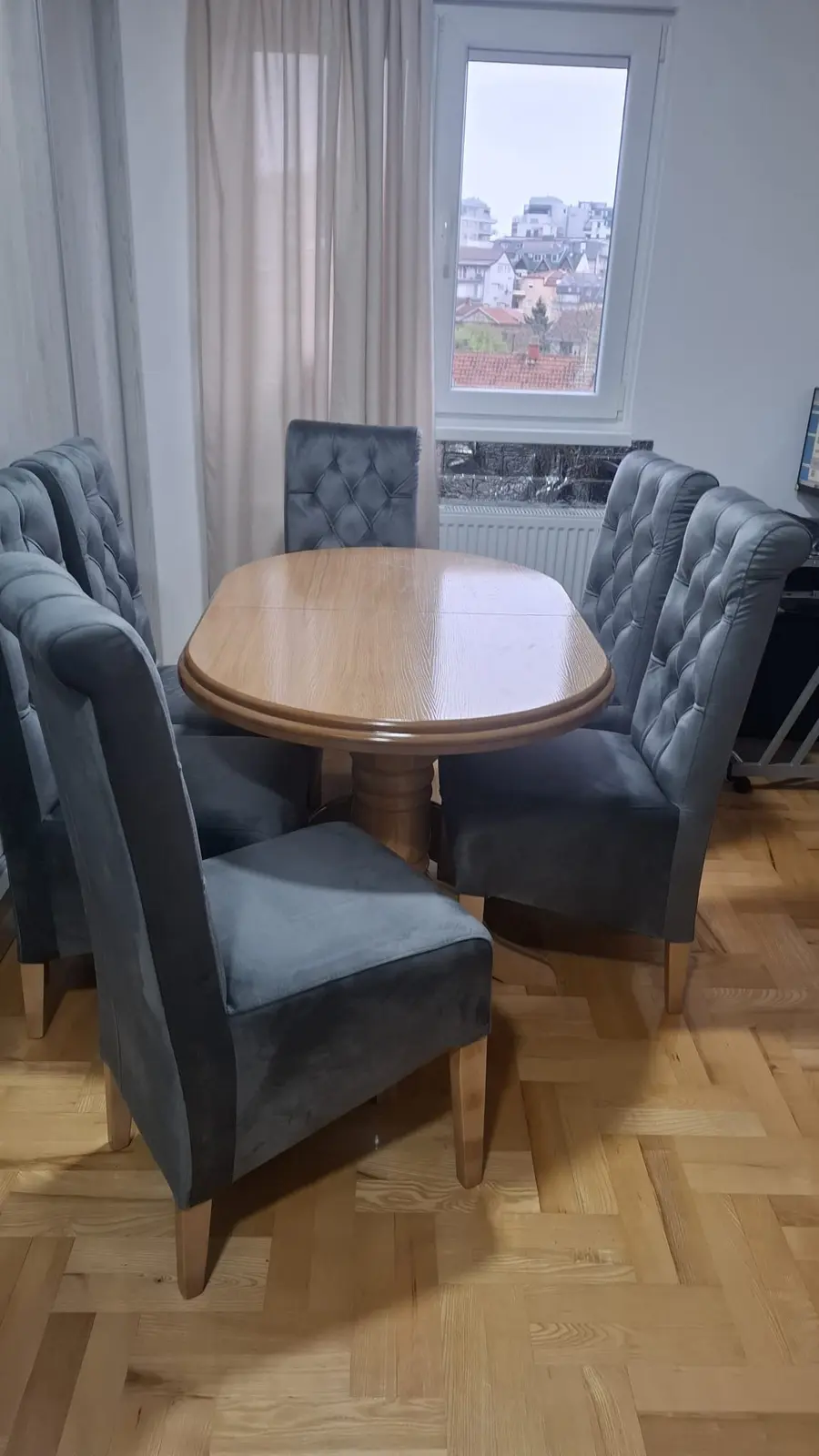 Ovalni drveni sto sa sivim tapaciranim stolicama